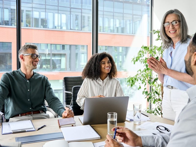 Happy diverse corporate team discussing project in boardroom office.